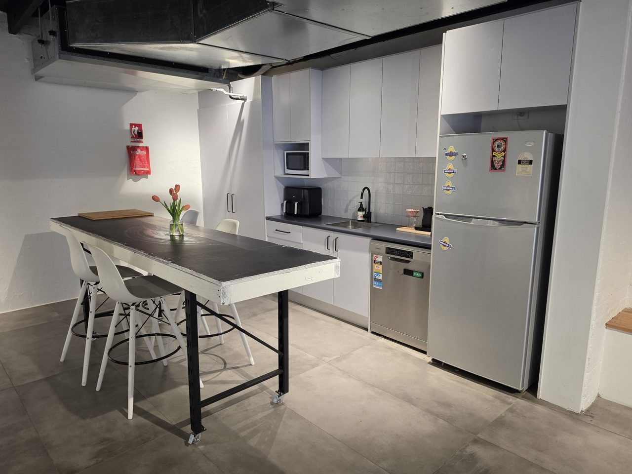 The island table set with tulips, kitchen bench and full-height fridge behind.