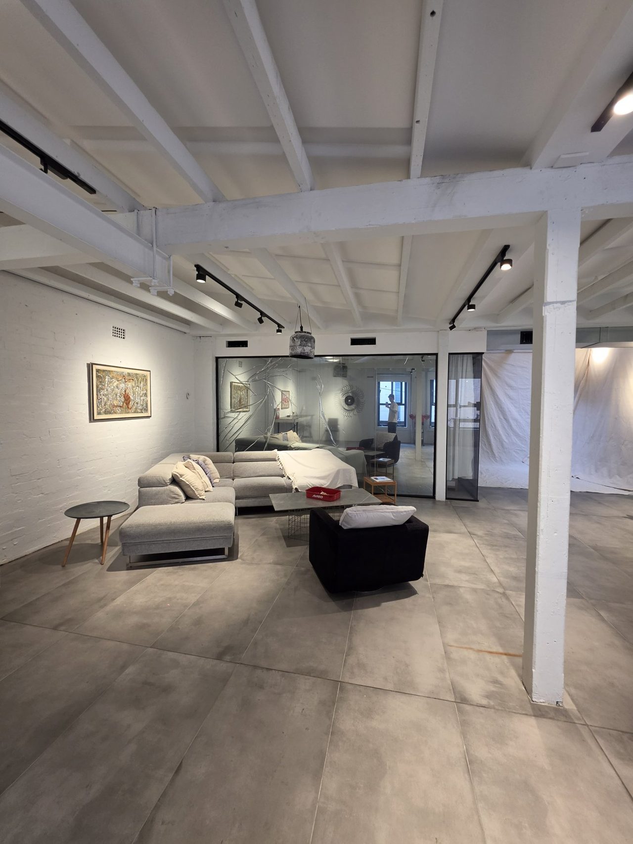 The loft lounge from the studio end — sofas and the glass room past the pillar.