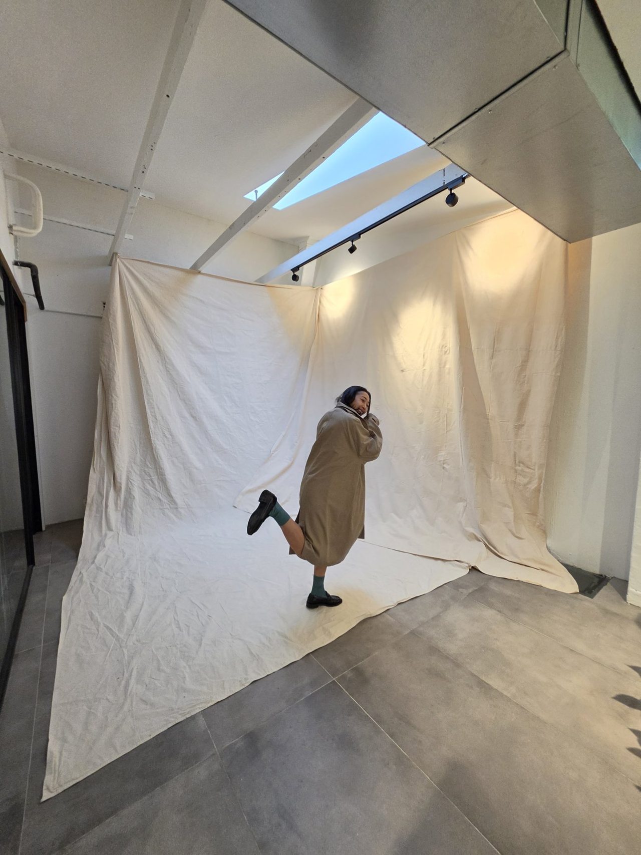 On the muslin backdrop under the skylight — mid-pose.
