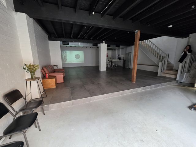 The whole ground floor seen from the loft stairs — platform, chairs out, kitchen at the back and the staircase in frame.
