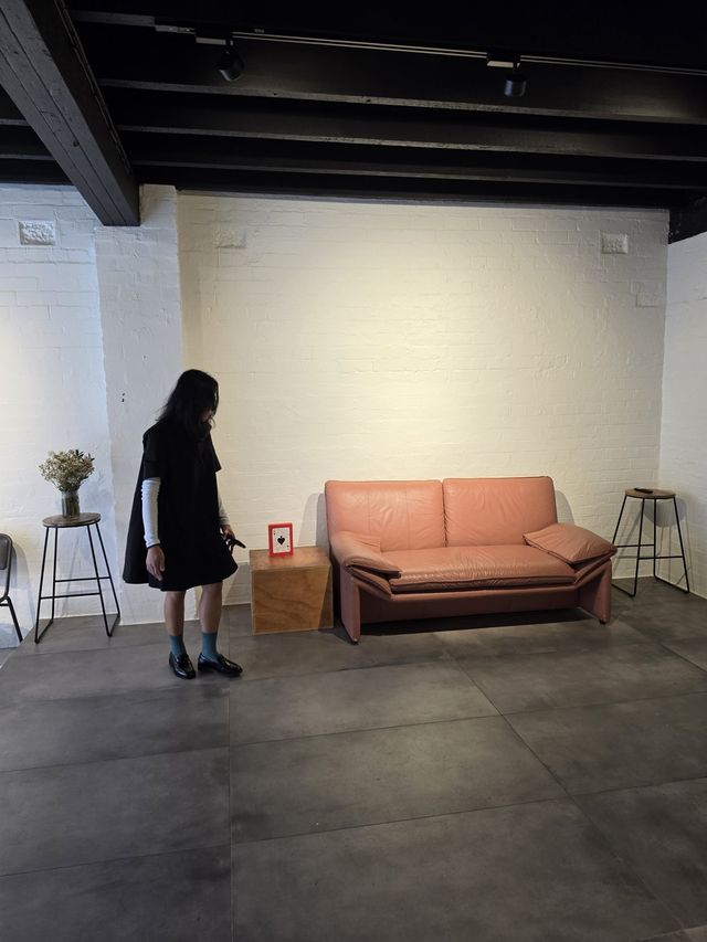 The terracotta sofa against white brick — someone lingering beside it.