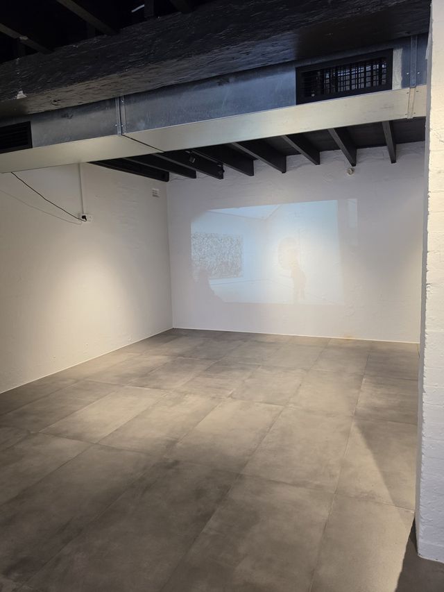 The projection glowing on the far wall, staircase alongside.