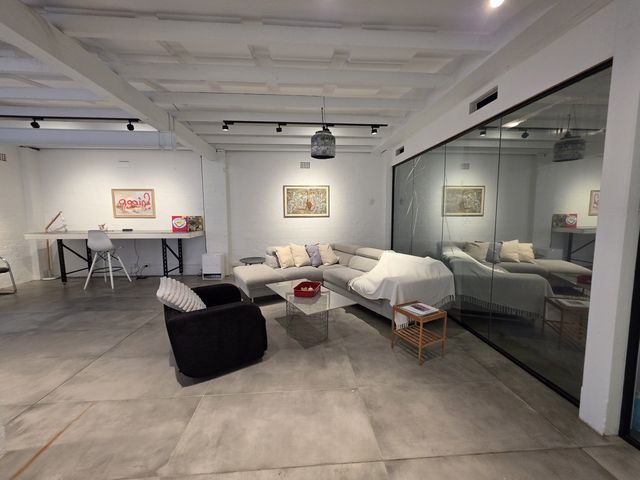 The loft lounge in one frame — sectional sofas, glass meeting room, gallery wall.