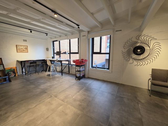 The loft floor full length — work tables, tall windows, sunburst sculpture.