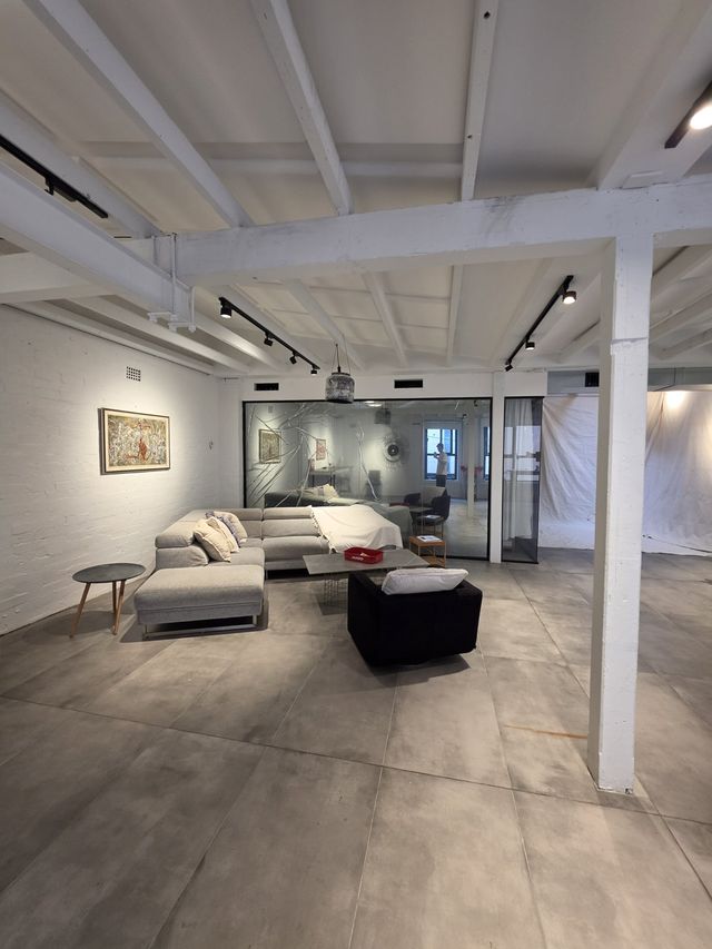 The loft lounge from the studio end — sofas and the glass room past the pillar.