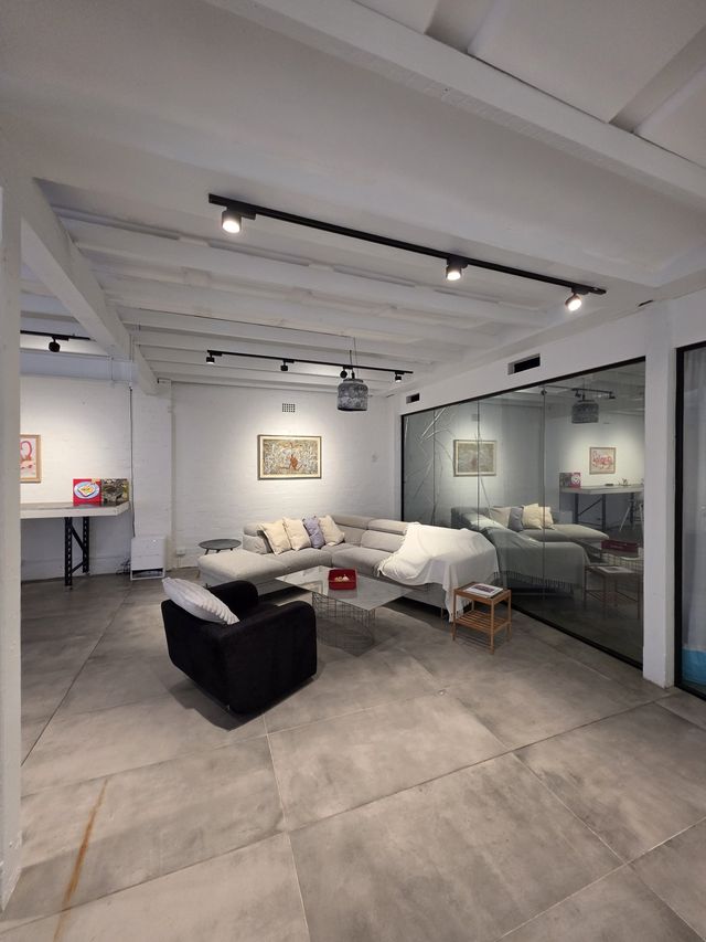 The loft lounge seen from above — sofas, glass room and gallery wall.