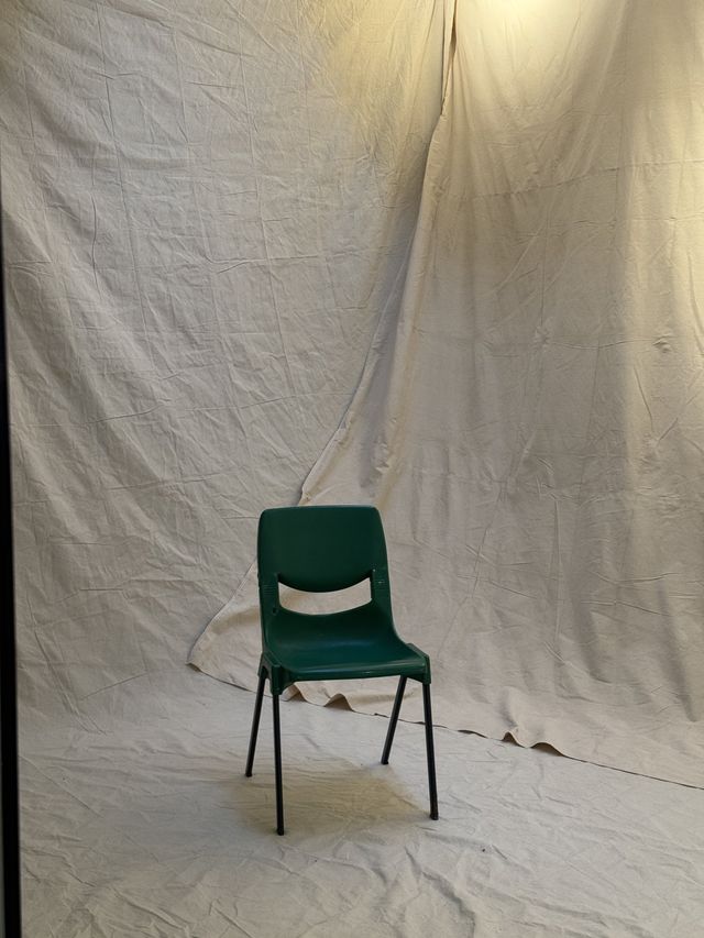 A green chair on the muslin — the frame that starts a shoot.
