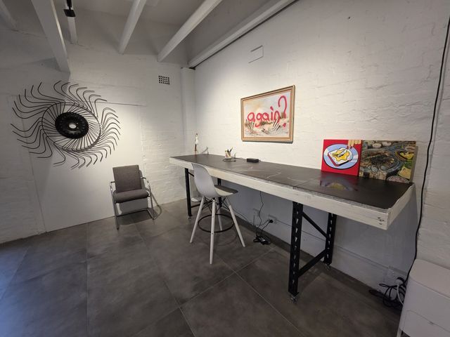 The work table under the sunburst sculpture and framed painting.